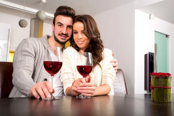 Um jovem casal desfrutando de um copo de vinho em casa — Fotografia de Stock