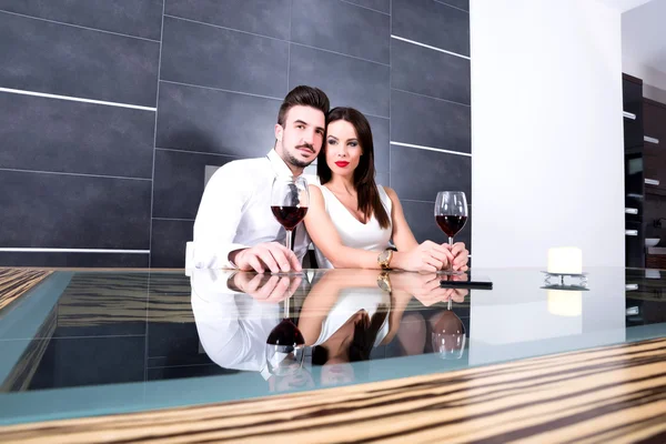 A romantic couple with a glass of wine in the dining room — Stock Photo, Image