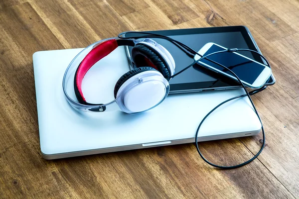 Dispositivos digitales y auriculares en un escritorio de madera —  Fotos de Stock