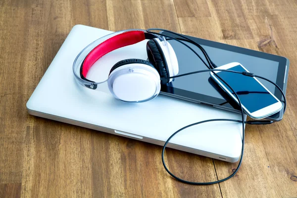Digitale Geräte und Kopfhörer auf einem hölzernen Schreibtisch — Stockfoto