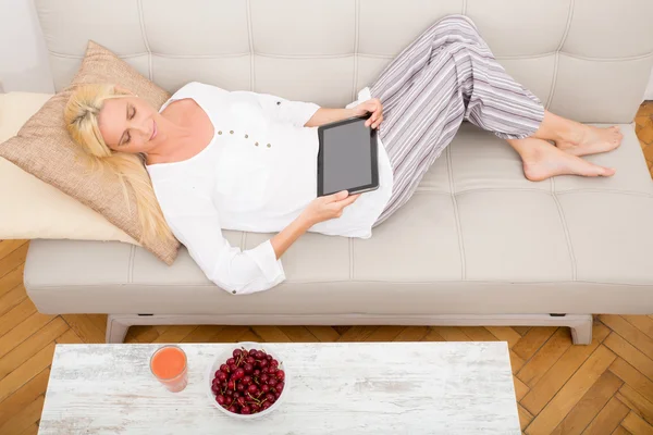 Mujer con tablet y cereza en el sofá — Foto de Stock