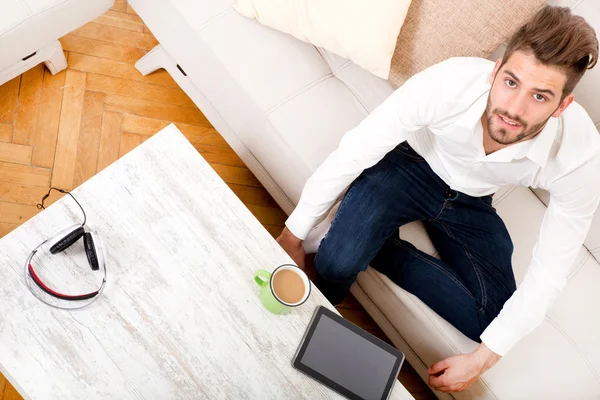 Jonge man met tablet op Bank — Stockfoto