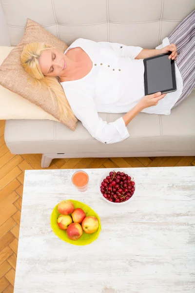 平板电脑和樱桃在沙发上的女人 — 图库照片