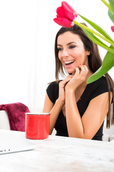 Jonge mooie vrouw die lacht tijdens het gebruik van een laptop thuis — Stockfoto