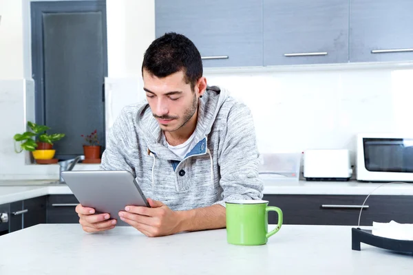 Jovem com tablet na cozinha — Fotografia de Stock