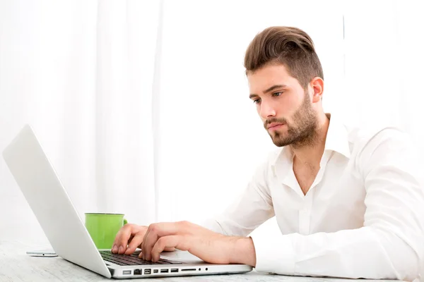 Jovem macho em casa com um laptop — Fotografia de Stock