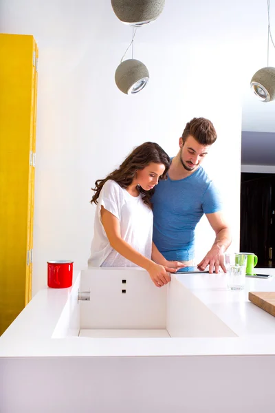 Pareja joven usando un Tablet PC en la cocina en casa —  Fotos de Stock