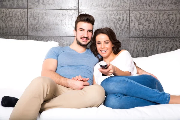 Pareja joven viendo una divertida película juntos en el sofá — Foto de Stock