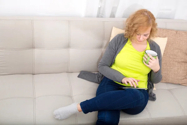 Молодая женщина с планшетным ПК на диване — стоковое фото
