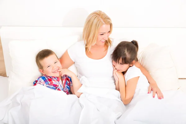 Moeder met dochter en zoon ontspannen in bed — Stockfoto