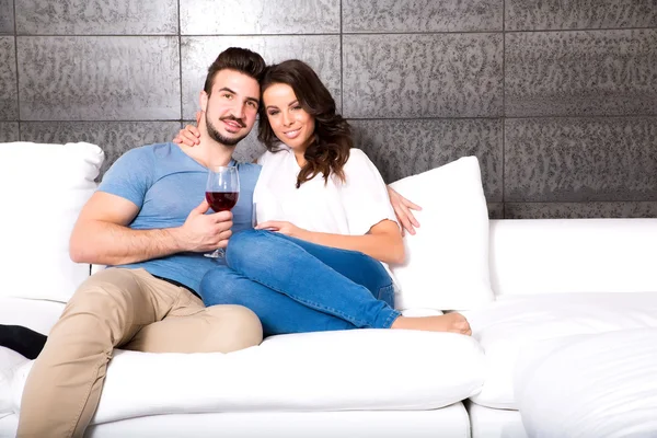 Красива пара насолоджується келихом вина на дивані — стокове фото