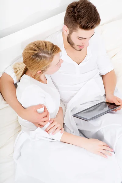 Jeune couple avec une tablette PC au lit — Photo