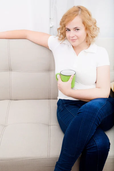 Молодая женщина с чашкой кофе на диване — стоковое фото