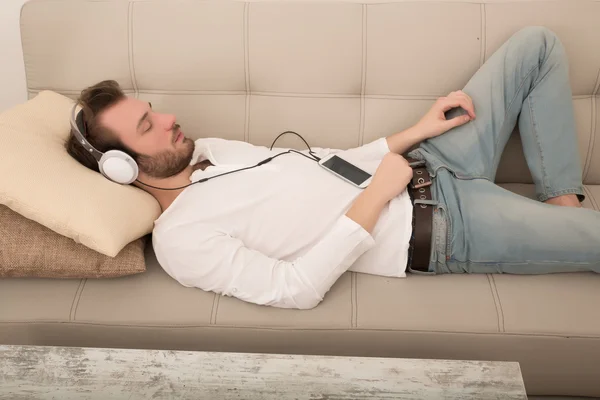 Young man listening to music on the sofa — Stock Photo, Image