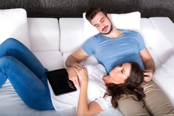 一对年轻夫妇在家里的沙发上一起使用平板电脑 — 图库照片