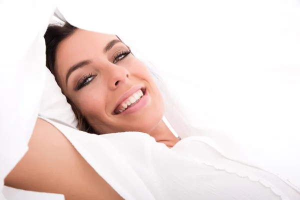 A beautiful young woman under the sheets in the bed — Stock Photo, Image