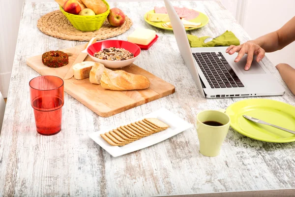 Giovane donna che fa colazione mentre utilizza un computer portatile — Foto Stock