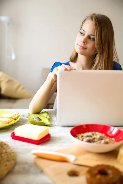 Młoda kobieta o śniadanie podczas korzystania z komputera przenośnego — Zdjęcie stockowe