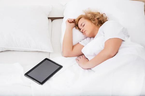 Jovem mulher dormindo na cama com um Tablet PC — Fotografia de Stock