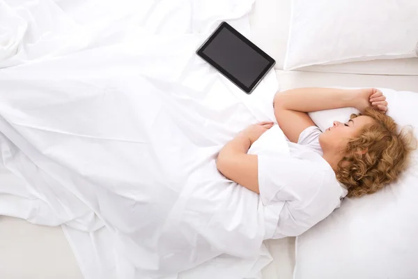 Mujer joven durmiendo en la cama con una tableta PC — Foto de Stock