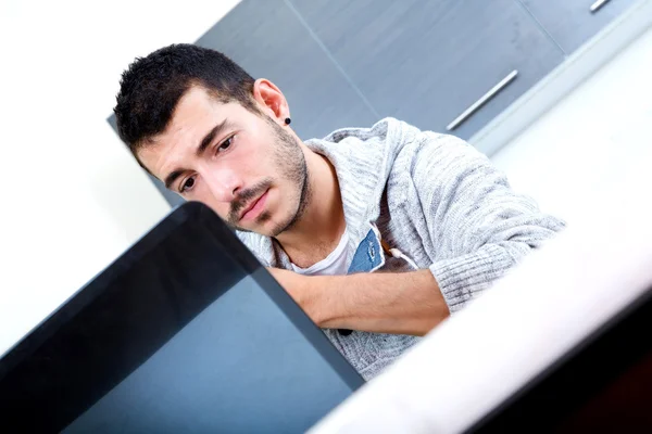 Mladý muž s notebookem v kuchyni — Stock fotografie