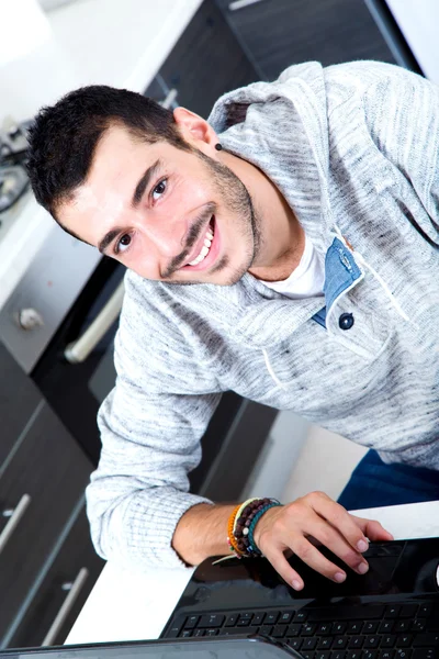 Молодой человек с ноутбуком на кухне — стоковое фото