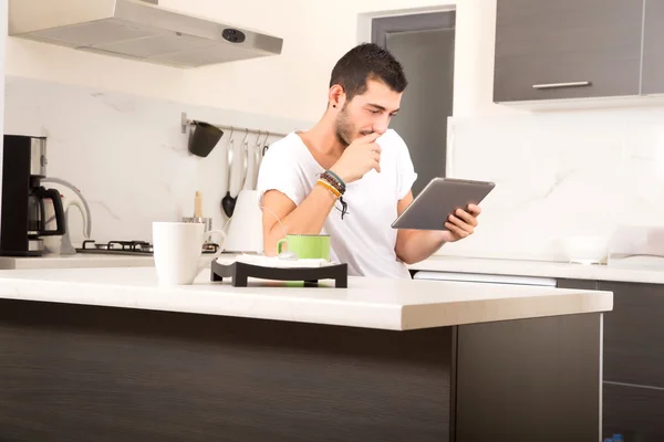 Jovem com tablet na cozinha — Fotografia de Stock