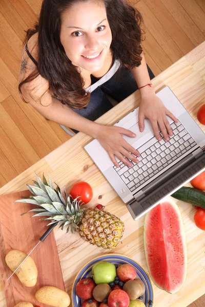 Mulher usando um laptop enquanto cozinha — Fotografia de Stock