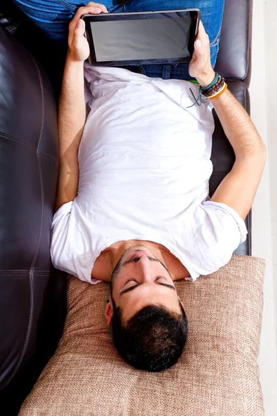 Young male with tablet on a couch — Stock Photo, Image