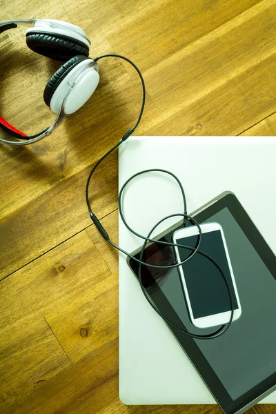 Dispositivos digitales y auriculares en un escritorio de madera —  Fotos de Stock