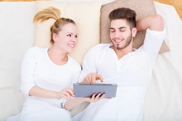Jeune couple avec une tablette PC au lit — Photo
