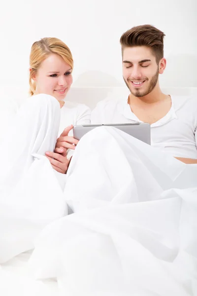 Jong koppel met een tablet-pc in bed — Stockfoto