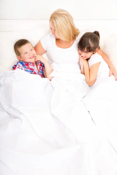 Mamma med dotter och son avkopplande i sängen — Stockfoto