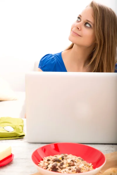 Молодая женщина, используя портативный компьютер после завтрака — стоковое фото
