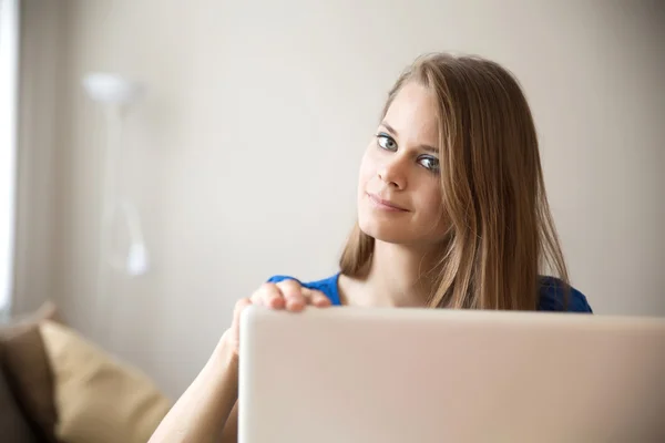 Mujer joven desayunando mientras usa una computadora portátil — Foto de Stock