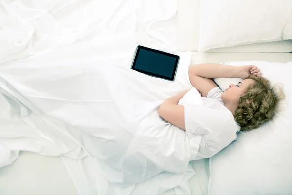 Junge Frau schläft mit Tablet-PC im Bett — Stockfoto