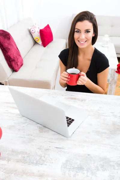 Jonge mooie vrouw met behulp van een laptop thuis — Stockfoto