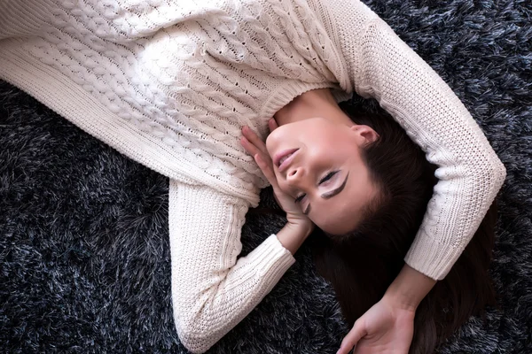 Junge, schöne Frau auf dem Teppich liegend — Stockfoto