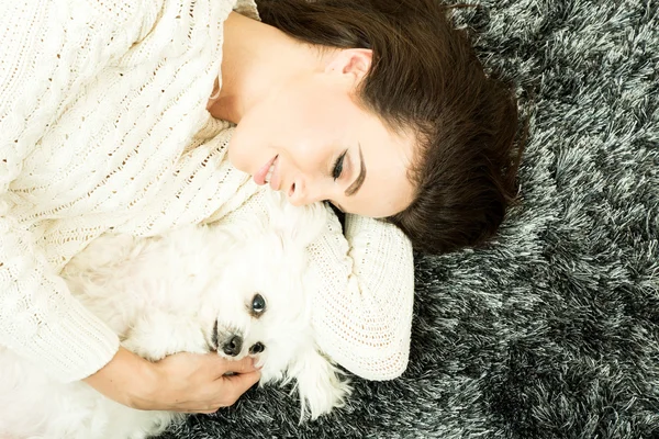 Jong mooi vrouw knuffelen haar hond op de tapijt — Stockfoto
