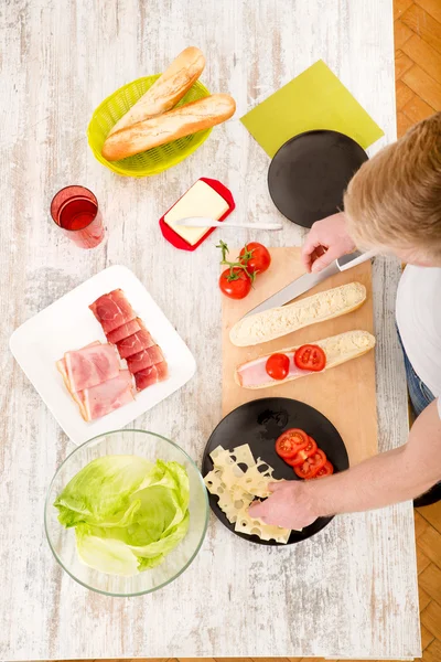 Jongeman bereidt een broodje voor — Stockfoto