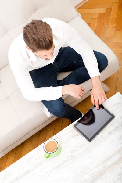 Ung man med tablett på soffan — Stockfoto