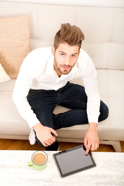 Hombre joven con tableta en el sofá — Foto de Stock