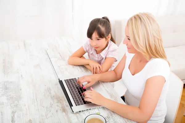 Mãe e filha com um laptop em casa — Fotografia de Stock