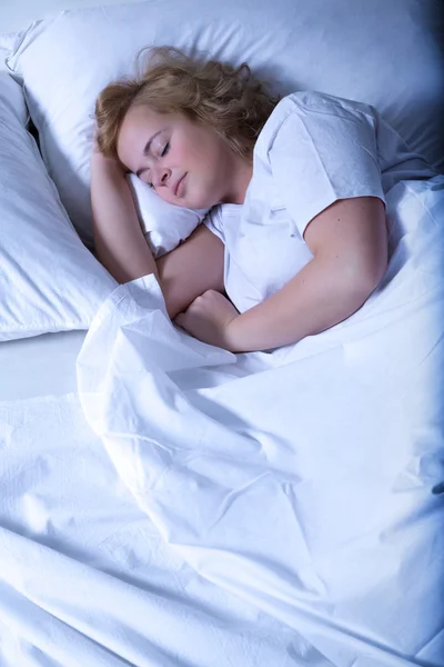 Молодая женщина спит в постели ночью — стоковое фото