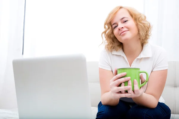 Giovane donna sul divano con gadget — Foto Stock