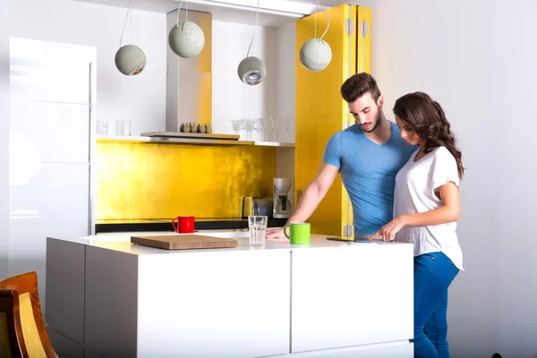 Pareja joven usando un Tablet PC en la cocina en casa —  Fotos de Stock