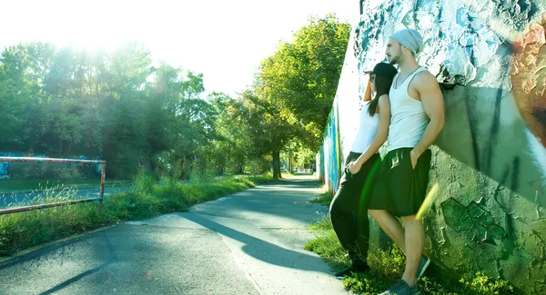 Pareja joven apoyada contra una pared en un entorno urbano — Foto de Stock