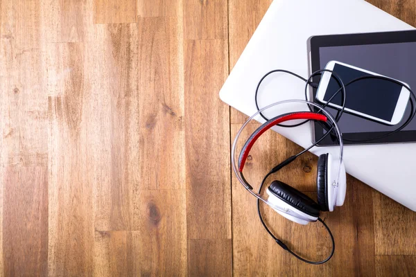 Dispositivos digitales y auriculares en un escritorio de madera —  Fotos de Stock