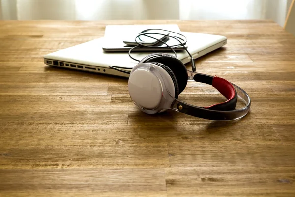 Dispositivos digitales y auriculares en un escritorio de madera —  Fotos de Stock