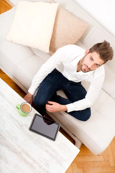 Young man with tablet on couch — Stock Photo, Image